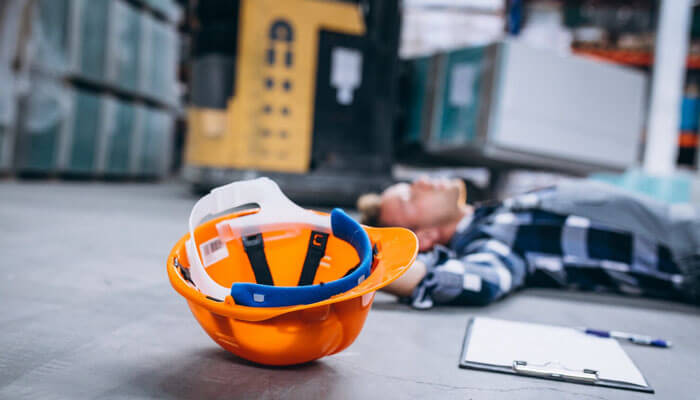 Fatigue monitoring prevents the accidents nobody plans for | tycoonstory media An abandoned orange safety helmet on the ground next to a worker who has fallen, highlighting the importance of smart gear for workplace safety and injury prevention.