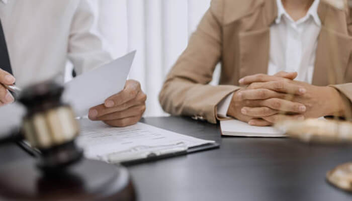 Challenging denials and filing appeals | tycoonstory media A lawyer and client discuss documents at a table, possibly related to challenging denials and filing appeals for disability benefits.
