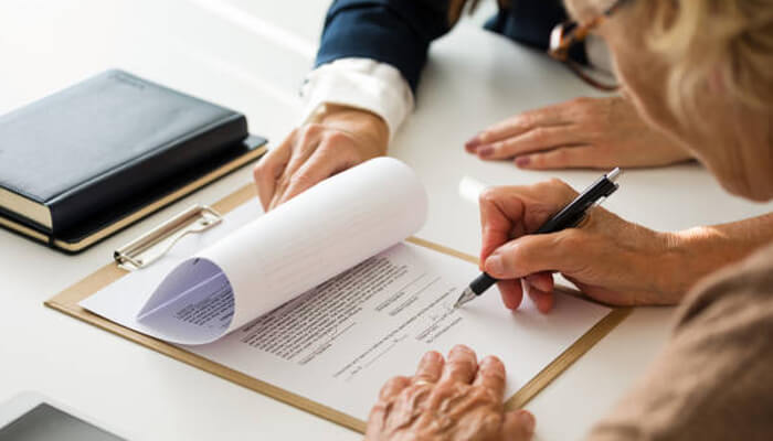 Changes to legal documents | tycoonstory media Two individuals signing legal documents in a professional setting, highlighting the importance of addressing financial elder abuse and safeguarding older adults' assets.