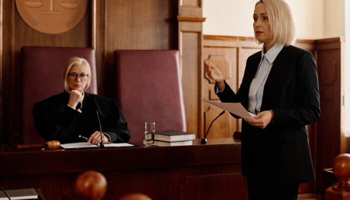 Clear and honest communication | tycoonstory media A courtroom-proven lawyer presenting a case in court, speaking confidently while addressing the judge, with the opposing attorney seated in the background.