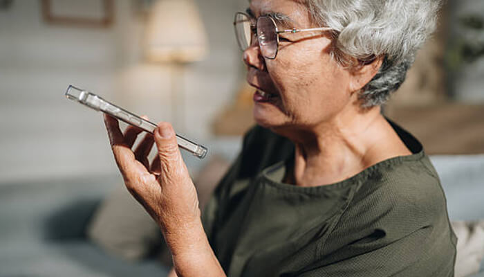 Comfortable design and easy handling | tycoonstory media An elderly woman using a user-friendly mobile phone, speaking into it with ease, showcasing the comfortable design and easy handling of user-friendly mobile phones.