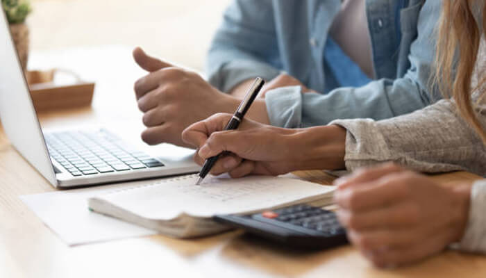Common issues credit repair can address | tycoonstory media Two people reviewing financial documents and making notes on a notebook, illustrating the process of credit repair and addressing common credit issues for financial improvement.