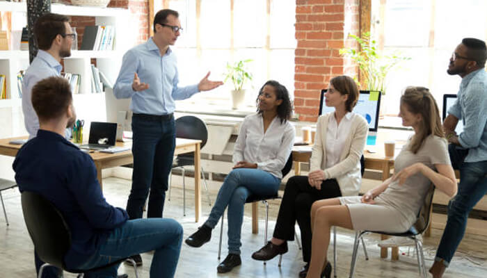 Developing strategic thinking | tycoonstory media A group of professionals in a business coaching session, with a leader guiding the team through a discussion. Participants are engaged, exchanging ideas to enhance strategic thinking.