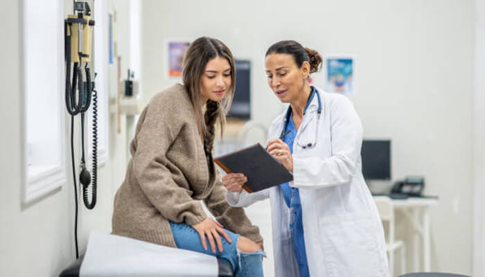 Encouraging preventive healthcare practices | tycoonstory media A healthcare professional discussing a medical report with a patient in a clinic, highlighting the importance of preventive healthcare practices covered under oshc for international students.