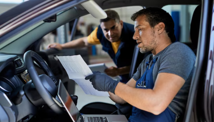 Checking driver records along with company policies | tycoonstory media Two mechanics review paperwork inside a vehicle, emphasizing how detailed documentation is vital for truck accident lawyers in strengthening accident claims.