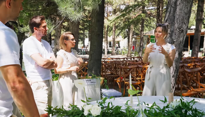 Expert event staff streamline planning | tycoonstory media An event planner discussing the setup at corporate event venues, explaining how to create a seamless experience for attendees in a beautiful outdoor setting.