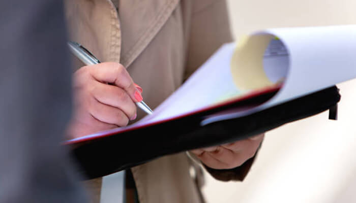 Filing a claim | tycoonstory media A person writing in a notebook, illustrating the process of filing a claim for a wrongful death case and the importance of proper documentation in legal proceedings.