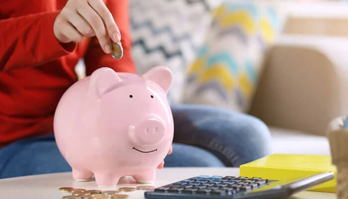 Automate the habit, even when the amounts feel small | tycoonstory media An image showing a person adding coins to a piggy bank, symbolizing the process of rebuilding your savings with careful planning and regular deposits for future financial security