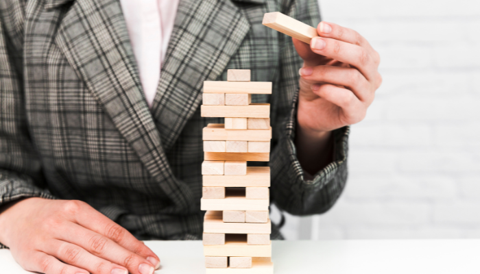 Why early action matters in criminal defense cases | tycoonstory media A person in a business suit carefully removes a block from a jenga tower, symbolizing the delicate balance and strategic decisions involved in managing criminal defense cases.
