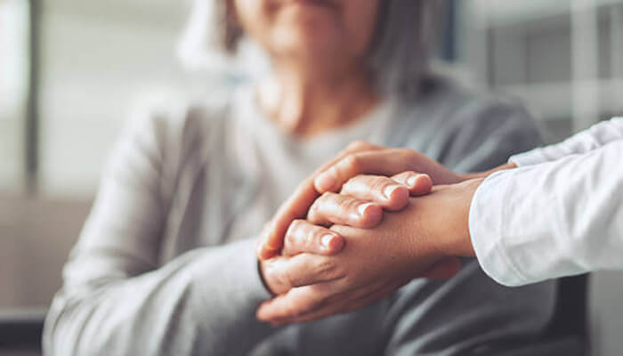 Improved health and well-being | tycoonstory media An elderly woman and a caregiver holding hands, symbolizing support and care. This image represents the compassionate environment of assisted living, focusing on emotional and physical well-being.