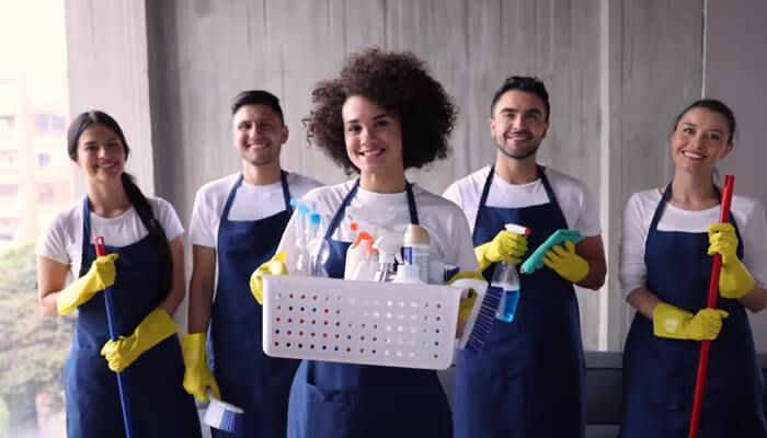 Jan-pro cleaning | tycoonstory media A team of professional cleaners wearing aprons and gloves, ready to provide high-quality commercial cleaning services with cleaning supplies in hand.