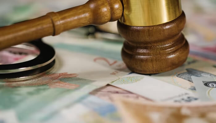 Legal defence costs | tycoonstory media A gavel on banknotes, symbolizing legal matters. This represents the need for professional indemnity insurance, which covers legal defense costs for professionals.