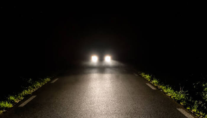 Lighting that matches how you actually ride | tycoonstory media Car headlights illuminating a dark road, highlighting the importance of lights after dark for safe nighttime driving and improved visibility.
