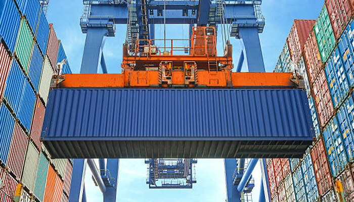 Mobility and relocation | tycoonstory media A crane lifting a 10ft shipping container at a busy port, showcasing the logistics and transportation of goods in global shipping and relocation processes.