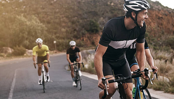 Reduced friction minimises discomfort over time | tycoonstory media Group of cyclists enjoying a ride on the road, showcasing the importance of quality cycling apparel for comfort and performance during long rides.