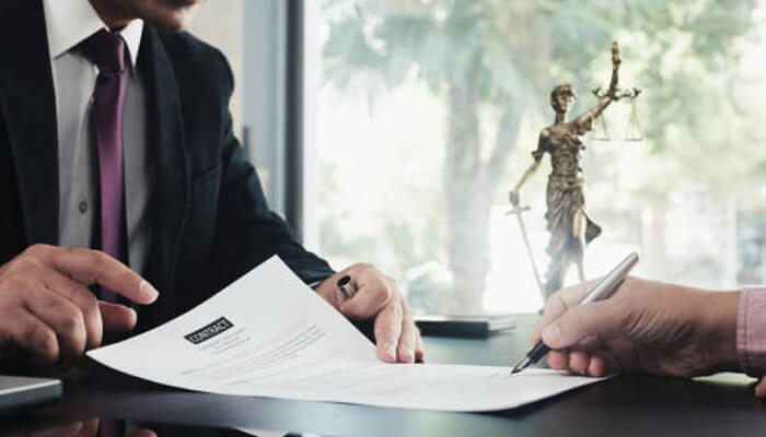 Reporting suspected abuse | tycoonstory media An individual signing a legal document with an attorney, symbolizing the process of reporting suspected facing elder abuse cases and seeking legal guidance for protection and justice.