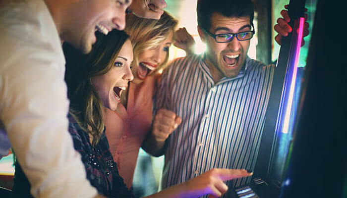 Slots | tycoonstory media Excited friends celebrating a win at the slot machine, enjoying the moment, possibly with slot free credit.
