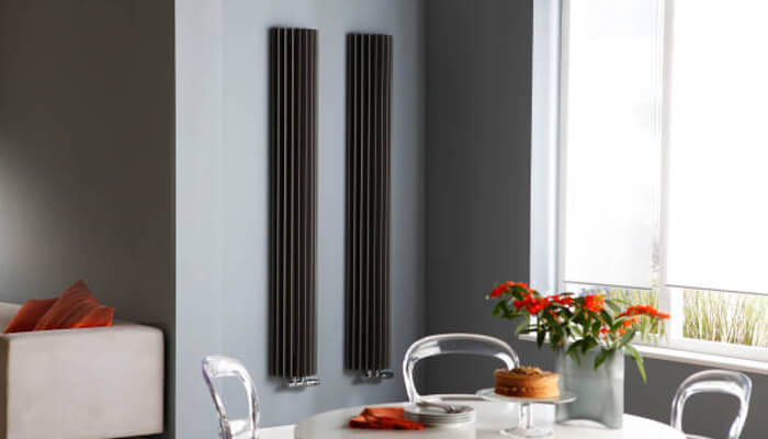 Smart heating and energy efficiency | tycoonstory media A modern dining space featuring sleek black designer radiators mounted on the wall, adding both style and functionality to the room while contributing to energy efficiency.