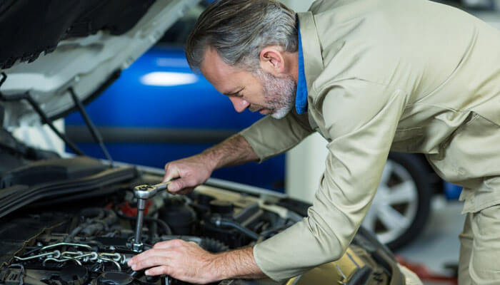 Tuning is the biggest bang for your buck | tycoonstory media A mechanic working on a ford powerstroke diesel truck, using a wrench to perform engine repairs in a well-lit garage.
