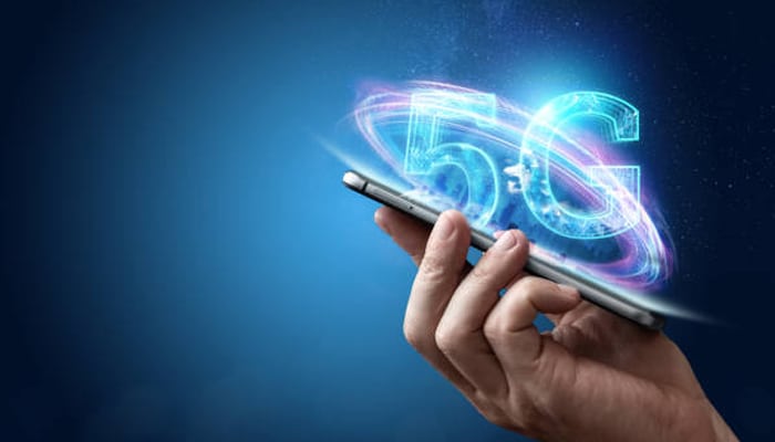 Untitled-1 | tycoonstory media Hand holding a smartphone with glowing 5g hologram emanating above it, symbolizing 5g connectivity on mobile devices.