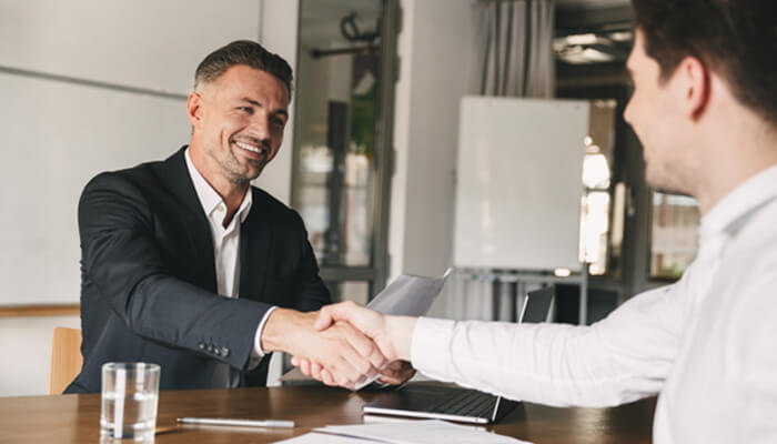 Dealing with the complex legal system | tycoonstory media Two professionals shaking hands in a business meeting, with a focus on building trust and collaboration, similar to the reliable service offered by san diego bail bonds.