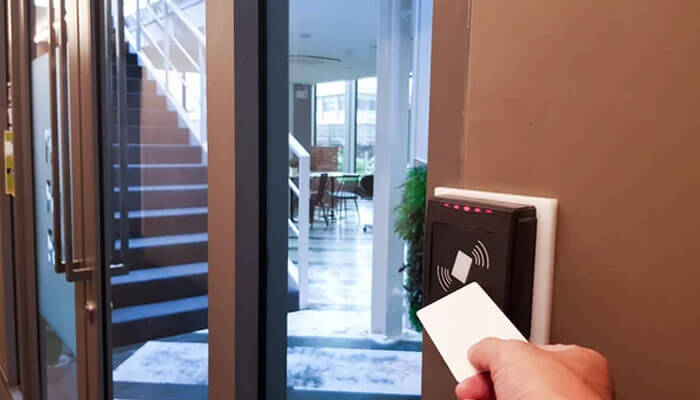 Controlled movement inside the building | tycoonstory media A person using a proximity access card to open a door, showcasing the security and convenience offered by proximity technology for controlled access.