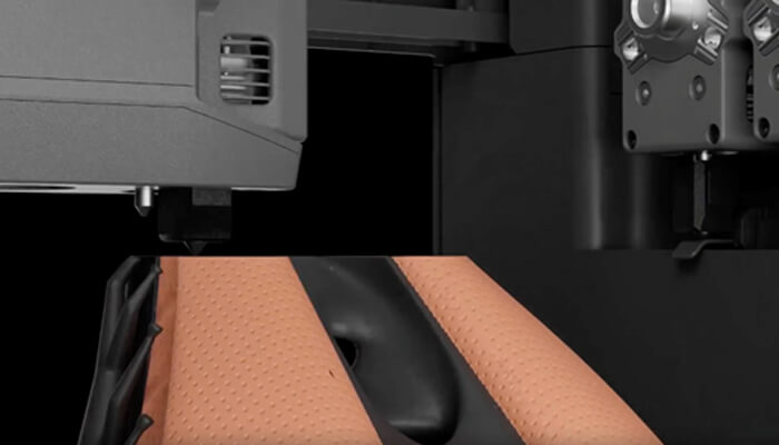 D 2 | tycoonstory media Close-up of industrial machine with orange perforated padding between black metal parts, suggesting a processing area or clamp mechanism.