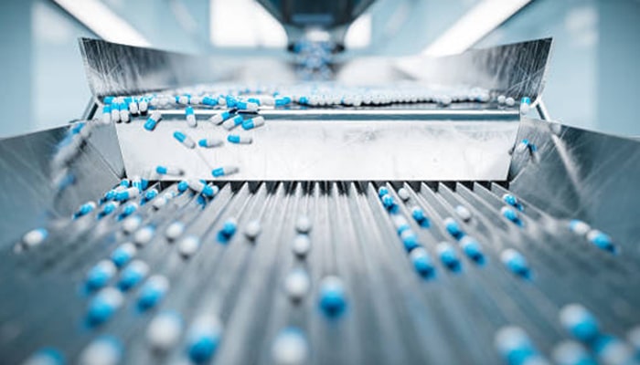Untitled-1 | tycoonstory media Capsules moving on production conveyor belt in automated system used by drug delivery comapanies for mass manufacturing.