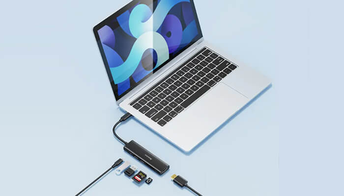 Best docking station for | tycoonstory media Laptop connected to a multi-port usb-c hub with sd cards and cables on a light blue background