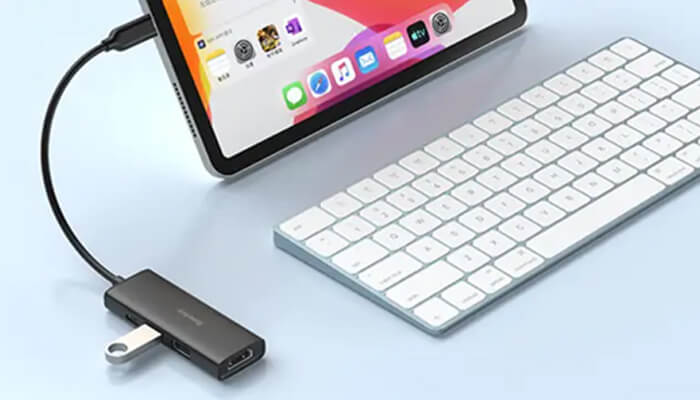 Best docking station | tycoonstory media Tablet connected to a usb-c hub with a white keyboard on a light blue desk surface.