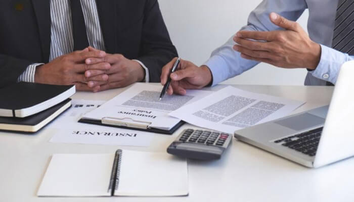 Negotiation with tax authorities in texas | tycoonstory media Two professionals discussing financial documents, possibly addressing delinquent tax penalties and business strategies in a formal setting.