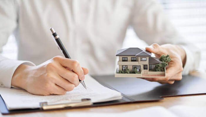 Check property type and structure | tycoonstory media Investor reviewing property documents while holding a model home, representing a careful approach to a tic investment.