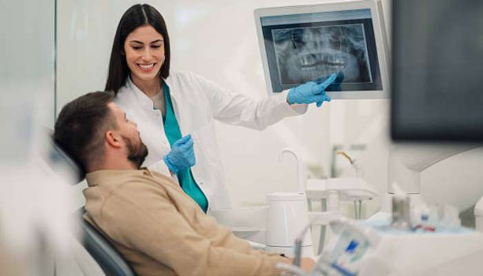 Dental professionals 1 | tycoonstory media Dentist wearing gloves shows a dental x-ray to a patient reclined in a clinic chair.