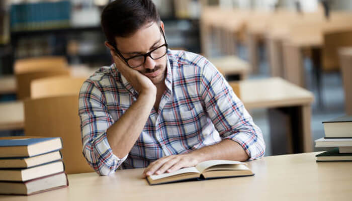 Why shorter reading sessions feel more manageable | tycoonstory media Student reading a book in a quiet library, showing flexible reading experiences for focused study and personal learning.