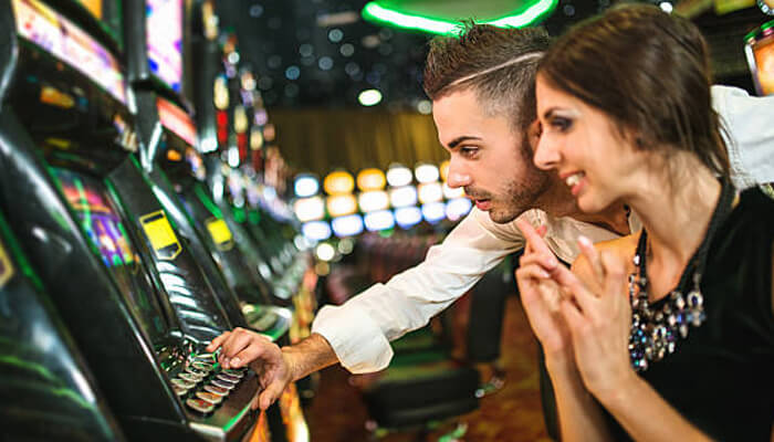 Choose your games strategically | tycoonstory media Couple enjoying slot machine games at a modern casino while exploring free credit rewards on mrlucky88 platform.