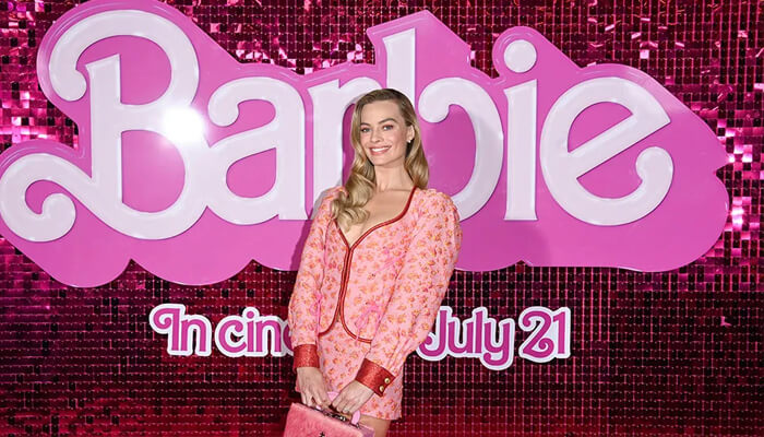 Barbie movie pr campaign | tycoonstory media Barbie movie pr campaign featuring a celebrity posing in front of a pink barbie backdrop, exemplifying successful pr campaigns that generate excitement and media coverage.