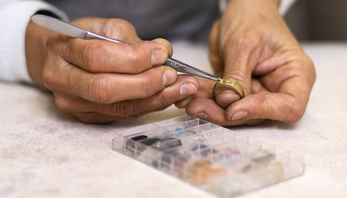 Design innovation and materials | tycoonstory media A jeweler carefully engraving a promise rings adding intricate details to the band, showcasing the craftsmanship involved in creating meaningful jewelry.