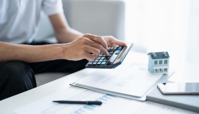 Homestead exemption cuts taxable amount | tycoonstory media A person calculating numbers with a calculator while reviewing documents, highlighting the importance of understanding property tax calculations.