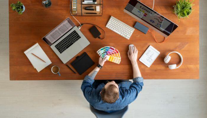 How to choose the best branding tools for your startup 1 | tycoonstory media Best branding tools for startups featuring startup designer workspace with branding software, color palettes, logo design, and creative branding tools