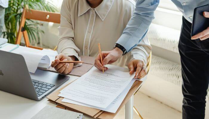 Notice of assignment and ucc filing 1 | tycoonstory media Business professionals signing invoice financing documents while discussing the advantages and disadvantages of factoring agreements