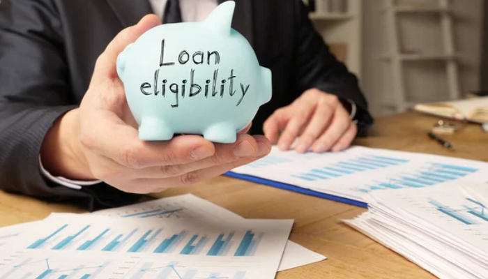 Startup loan | tycoonstory media Business professional holding a loan eligibility piggy bank symbol related to how to get a startup business loan with no money.