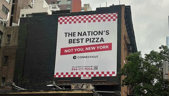 Connecticut tourism – pizza capital claim | tycoonstory media Connecticut tourism – pizza capital claim billboard mocking new york, exemplifying successful pr campaigns that draw attention through bold messaging.