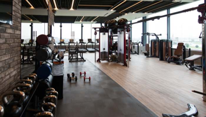 The equipment categories leading this shift | tycoonstory media Spacious gym with weight racks and free weights on the left, cardio machines at the back, and a central multi-station weight machine.