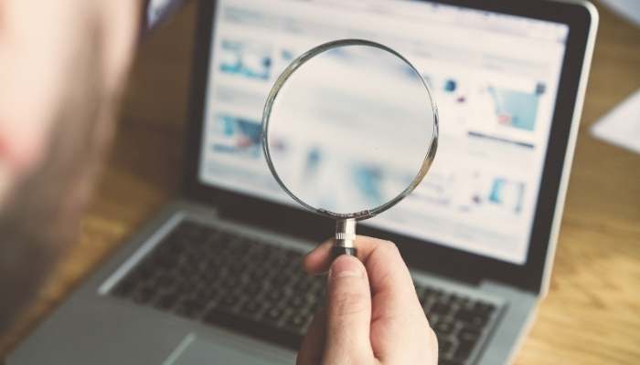 The nature of local search results | tycoonstory media Magnifying glass over a laptop screen showing digital marketing research, analytics, and online search strategy.