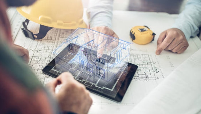 Untitled-1 | tycoonstory media Architects reviewing house model on tablet with bim digital overlay on construction blueprints for project planning.