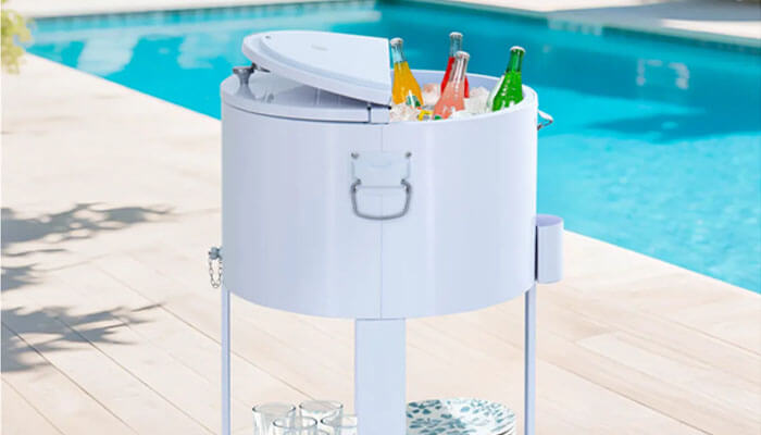 A cooler with wheels - tycoonstory | tycoonstory media Poolside white beverage cooler on a stand filled with bottles by a sunny poolside patio