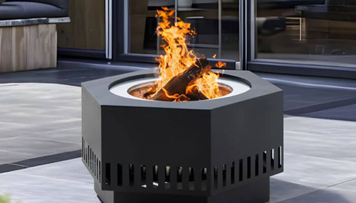 A fire pit - tycoonstory | tycoonstory media Modern square outdoor fire pit with bright flames on a patio in front of glass doors at a contemporary outdoor space.