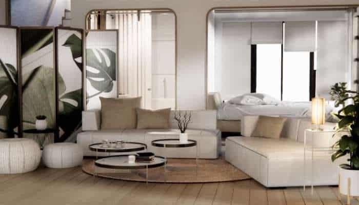 Acrylic furniture in compact living spaces 1 | tycoonstory media Open-plan living area with white sofas, round coffee tables, and a beige rug, leading to a bedroom area with a bed beyond a windowed divider.