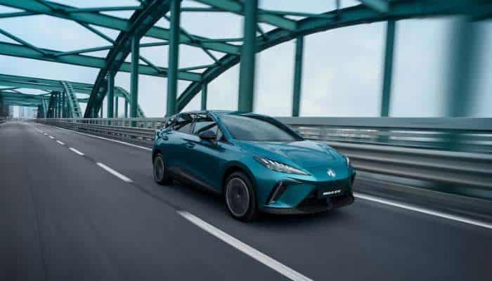 Best chinese electric cars in europe 2026 5 | tycoonstory media Blue-green peugeot car driving on a modern green steel arch bridge with lanes ahead.