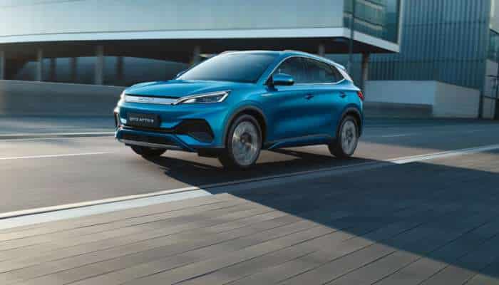 Best chinese electric cars in europe 2026 7 | tycoonstory media Blue electric suv driving on a city street with modern glass buildings in the background, daytime scene.